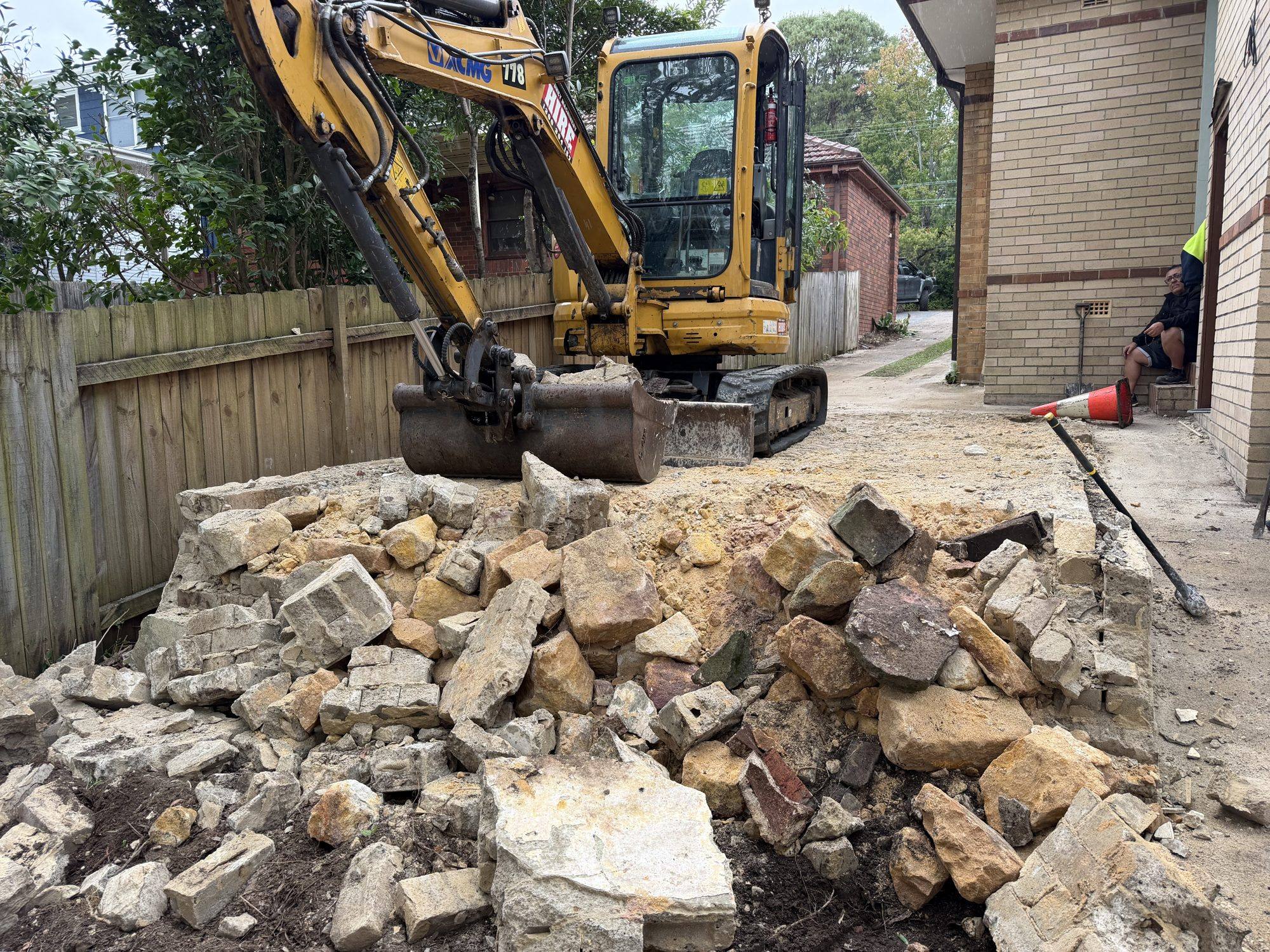 HazWreck excavator breaking a backyard garage into a rubble pile