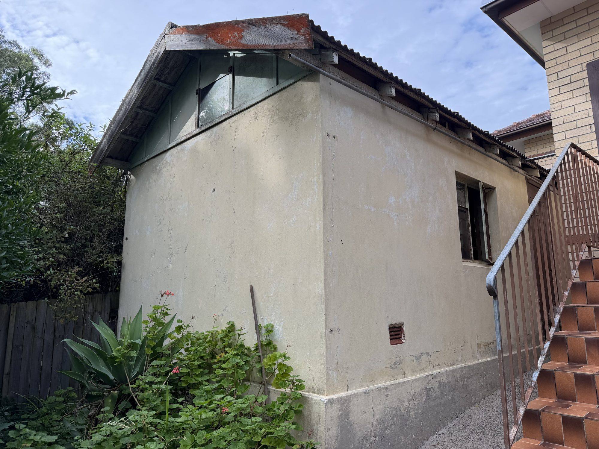 Old rendered backyard garage behind a brick home before demolition