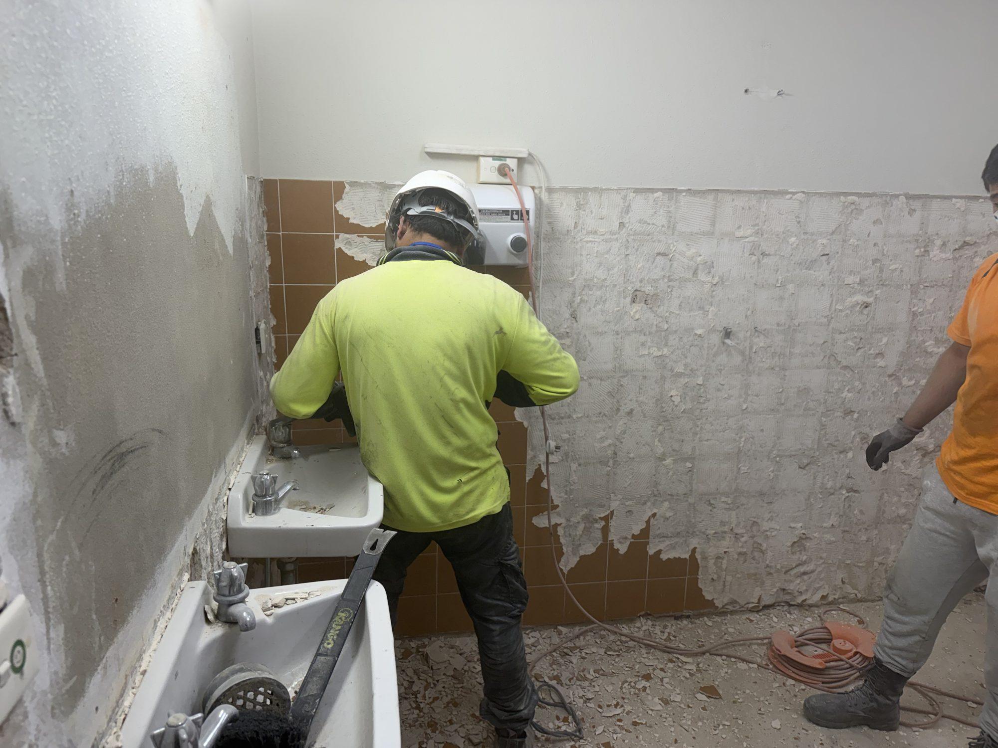 HazWreck crew stripping wall tiles and adhesive during a commercial amenities defit in Sydney