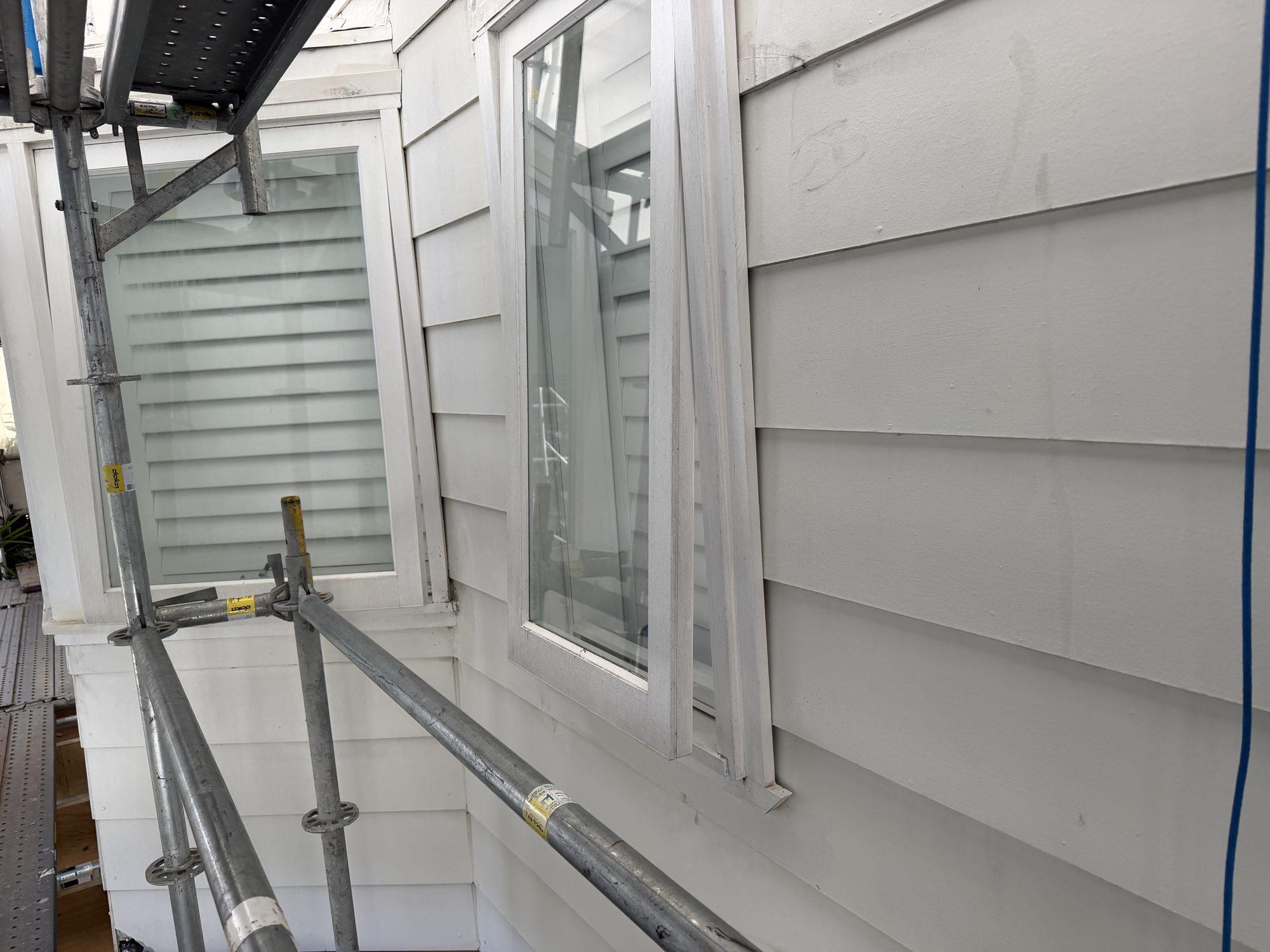 House elevation behind scaffold inside the wrap, windows sealed and protected during the works
