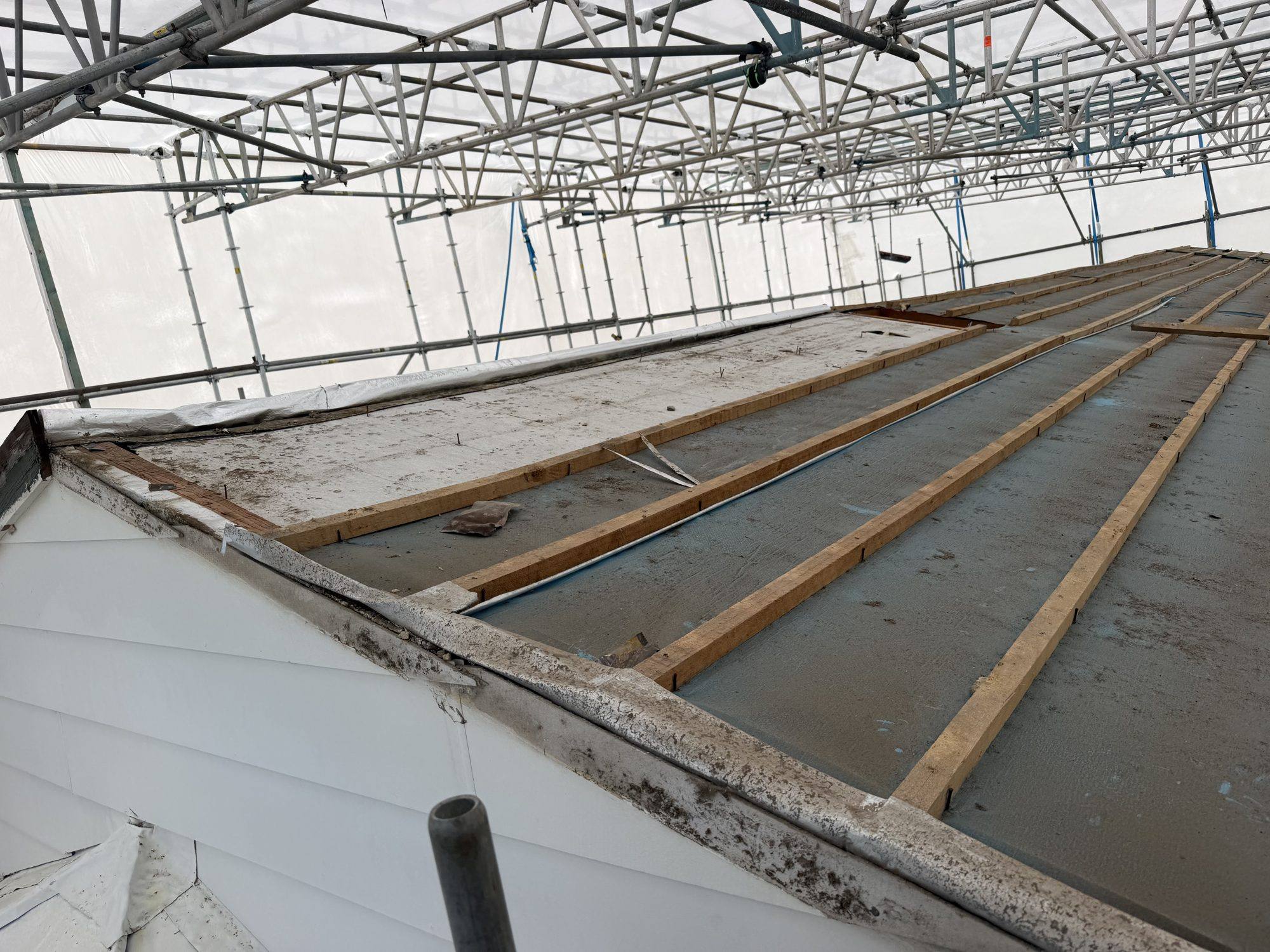 Asbestos cement roof sheeting PVA-sprayed under battens inside the scaffold wrap