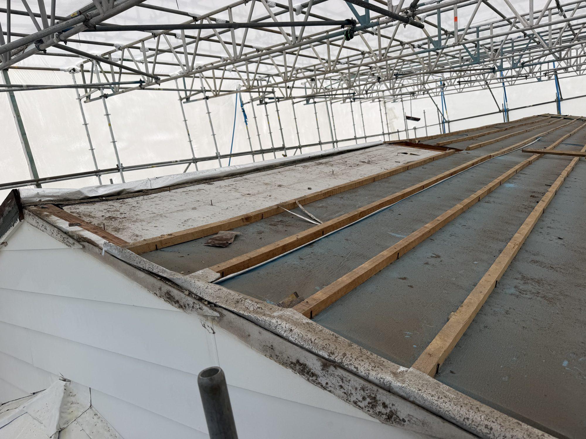 Asbestos cement roof sheeting sprayed with PVA sealant, exposed under battens inside the scaffold wrap canopy