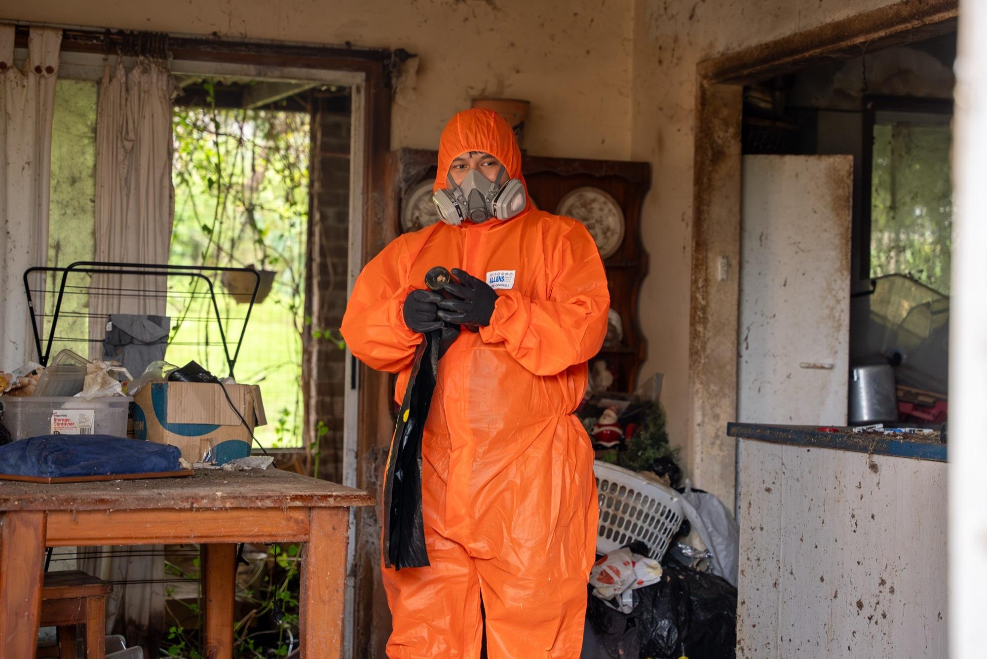 HazWreck crew member in PPE sorting contents in a hoarded Sydney living room