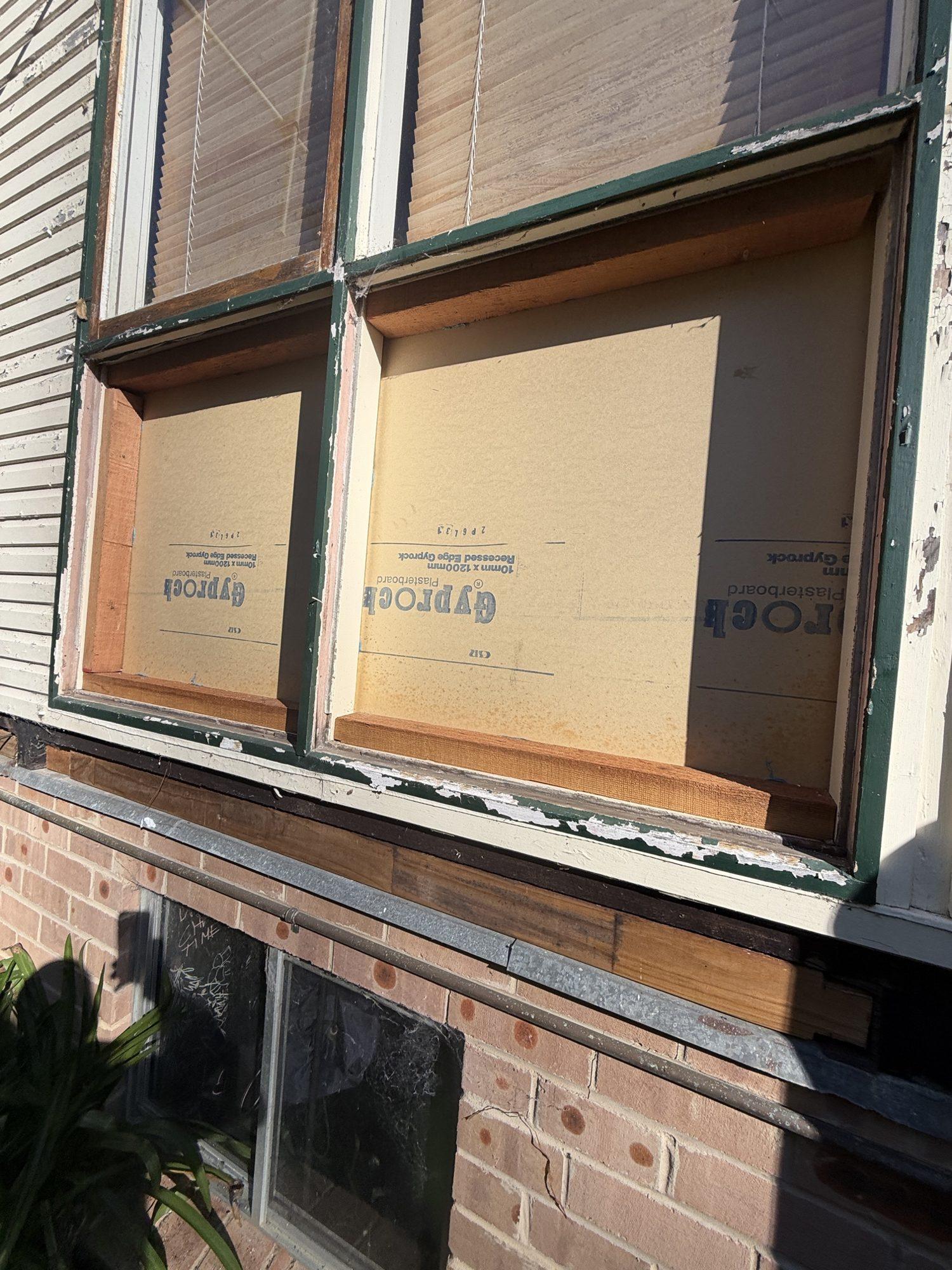 Window with the asbestos cladding removed and a temporary board fitted, ready for the builder