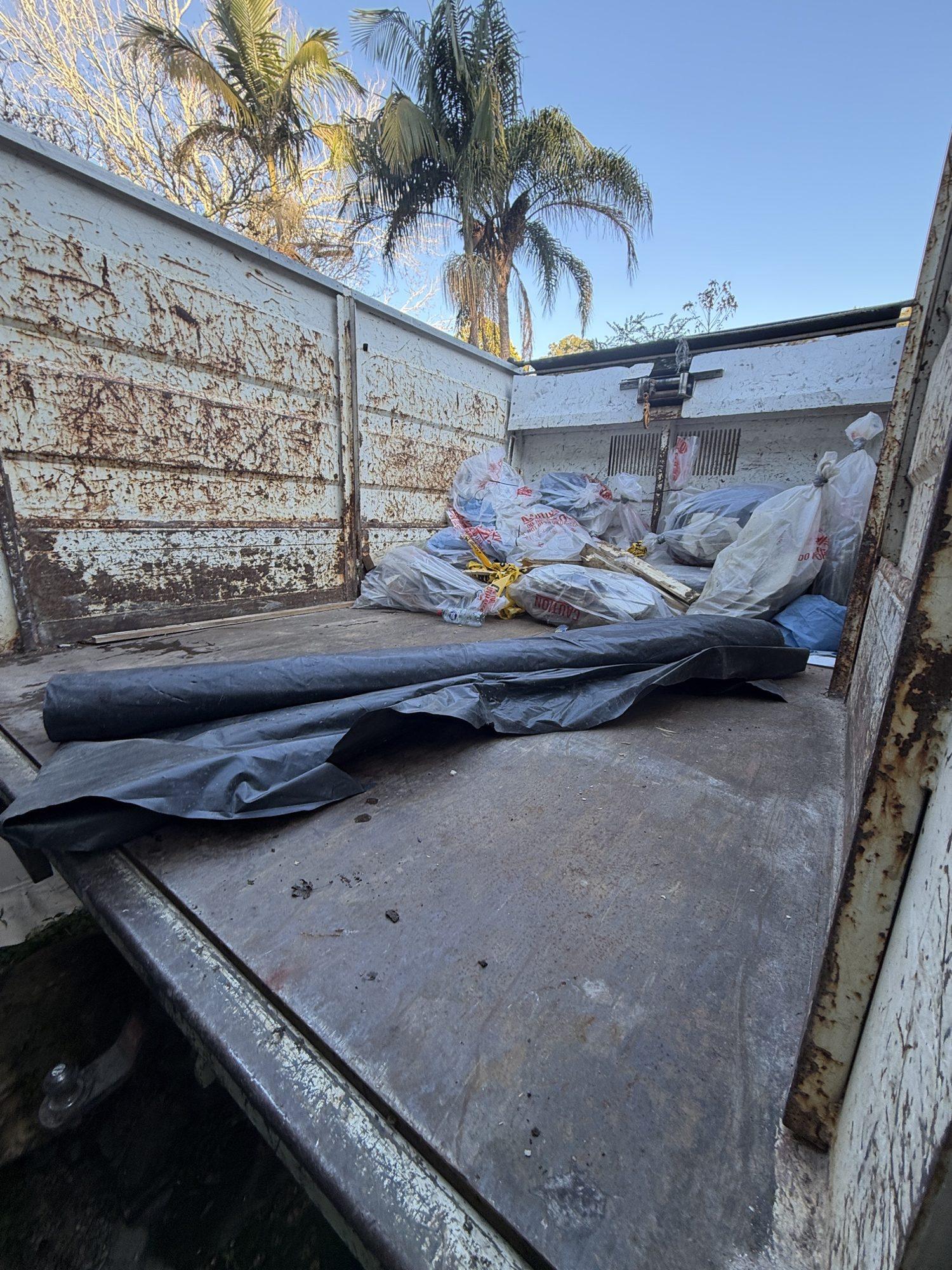 Wrapped and sealed asbestos sheets loaded on the HazWreck truck tray for transport