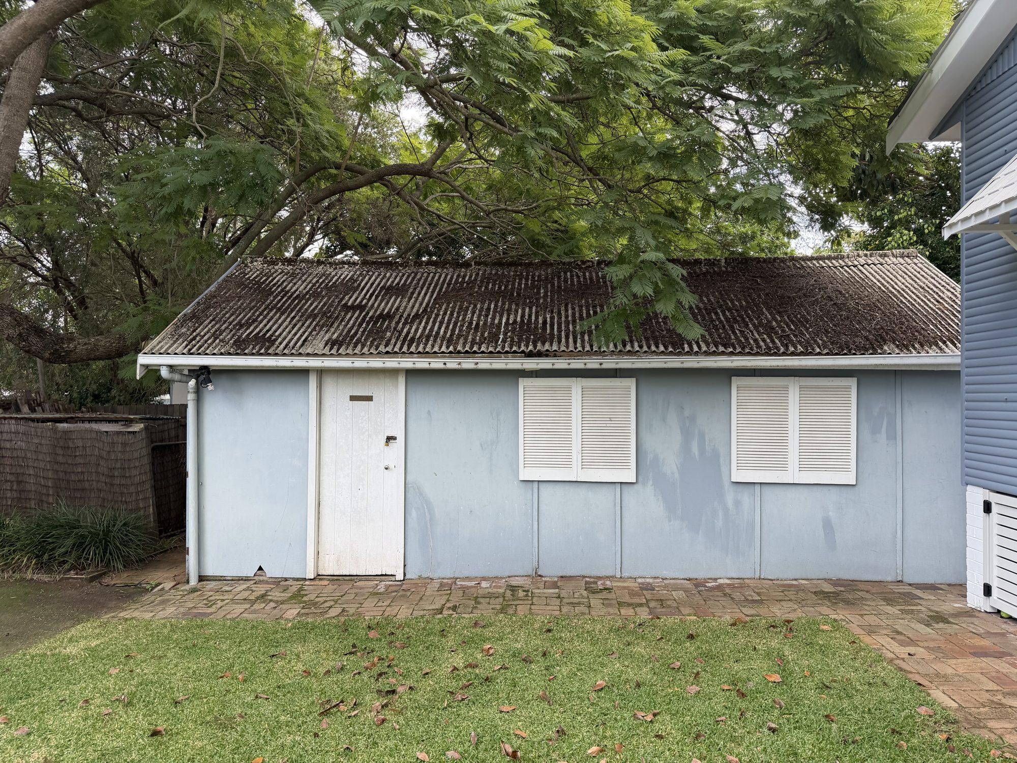 The long side of the garage showing the weathered, lichen-covered Super Six asbestos roof