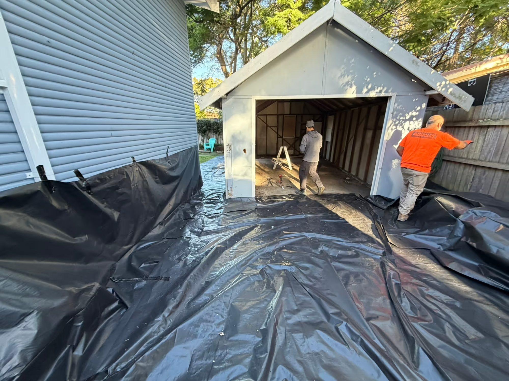 HazWreck crew stripping the garage with ground sheeting laid across the work area