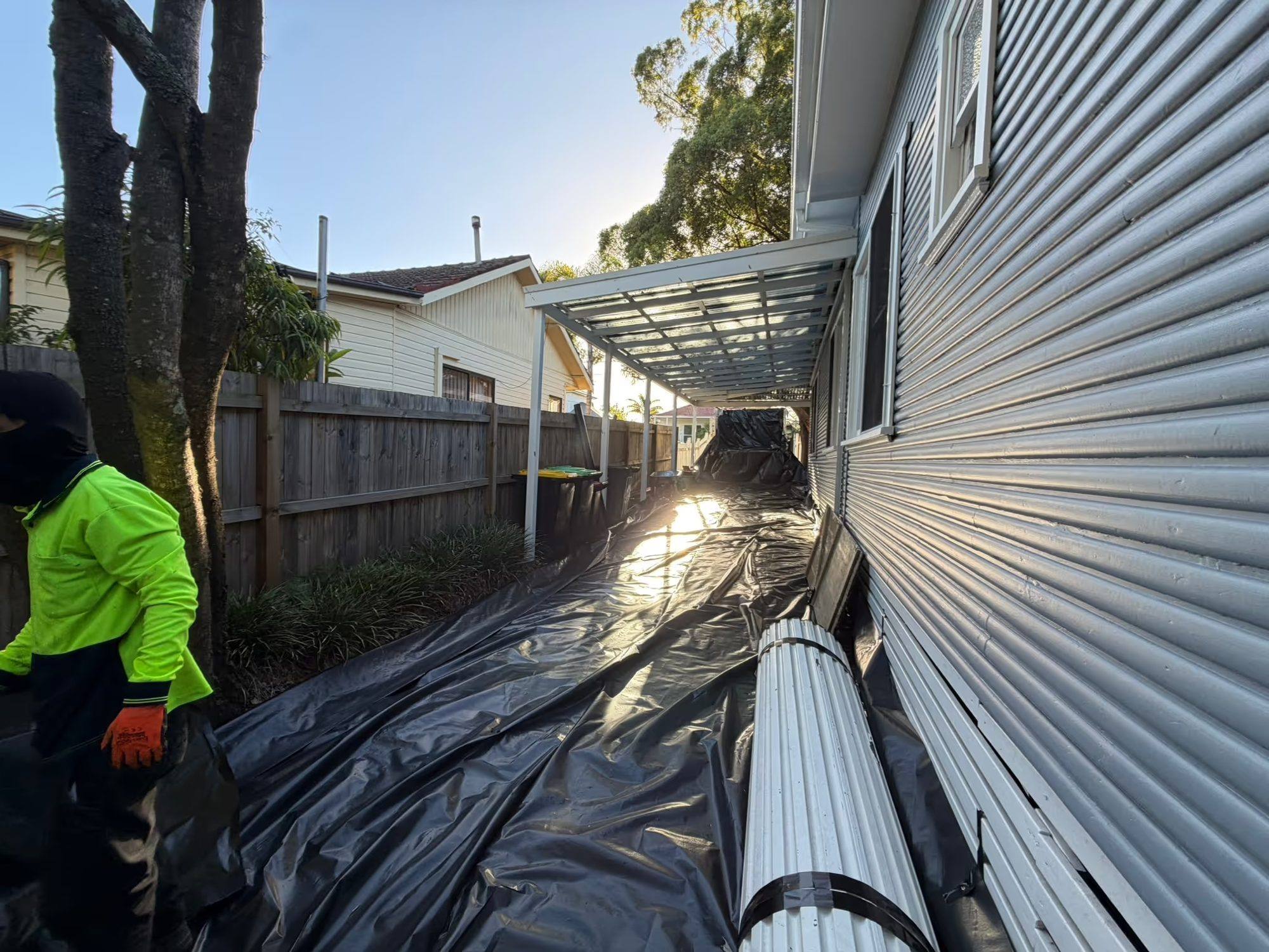 HazWreck crew member carrying Super Six roof sheets down the sheeted side path