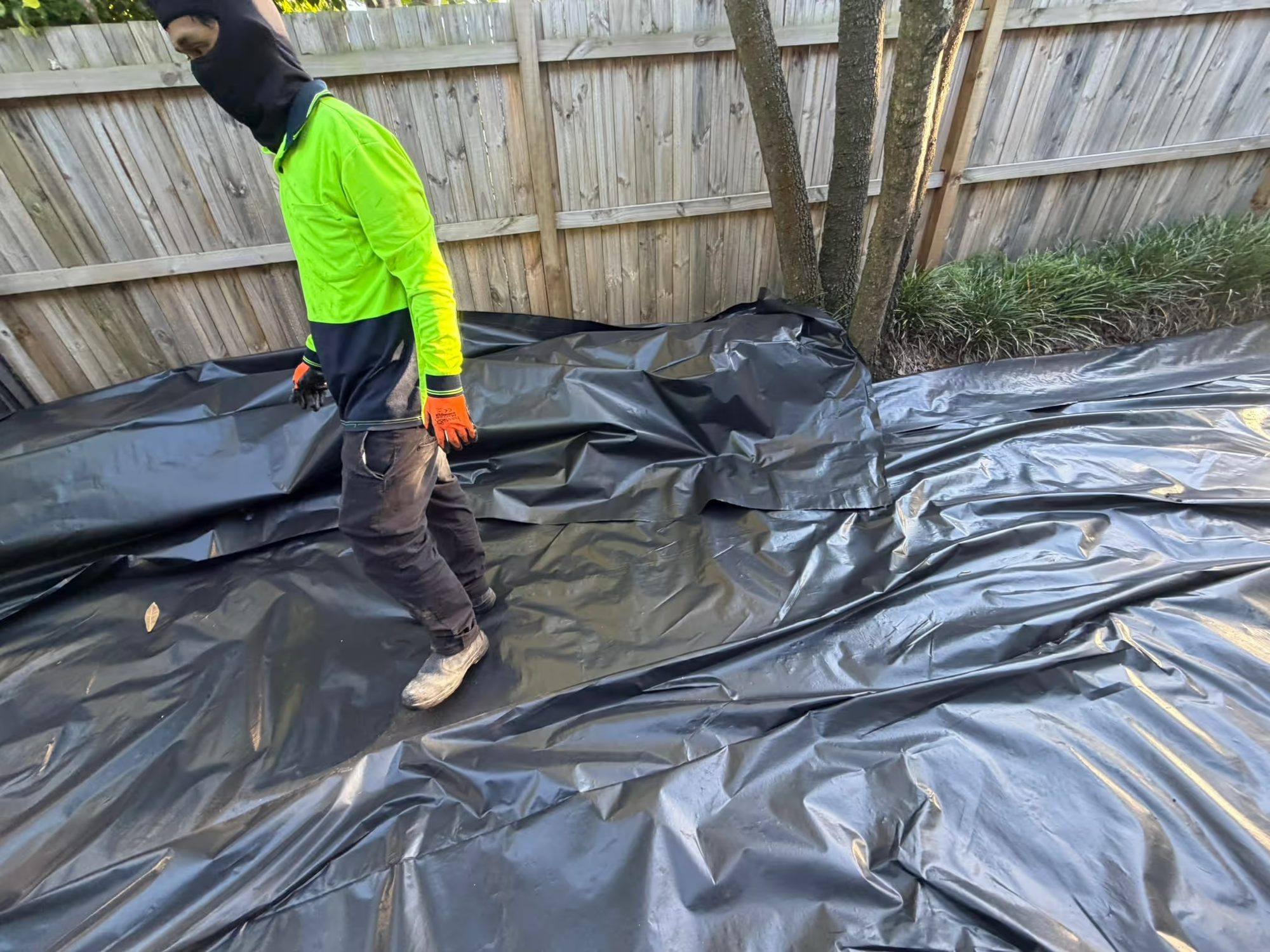 Removed asbestos sheeting laid on heavy plastic for double-wrapping on site