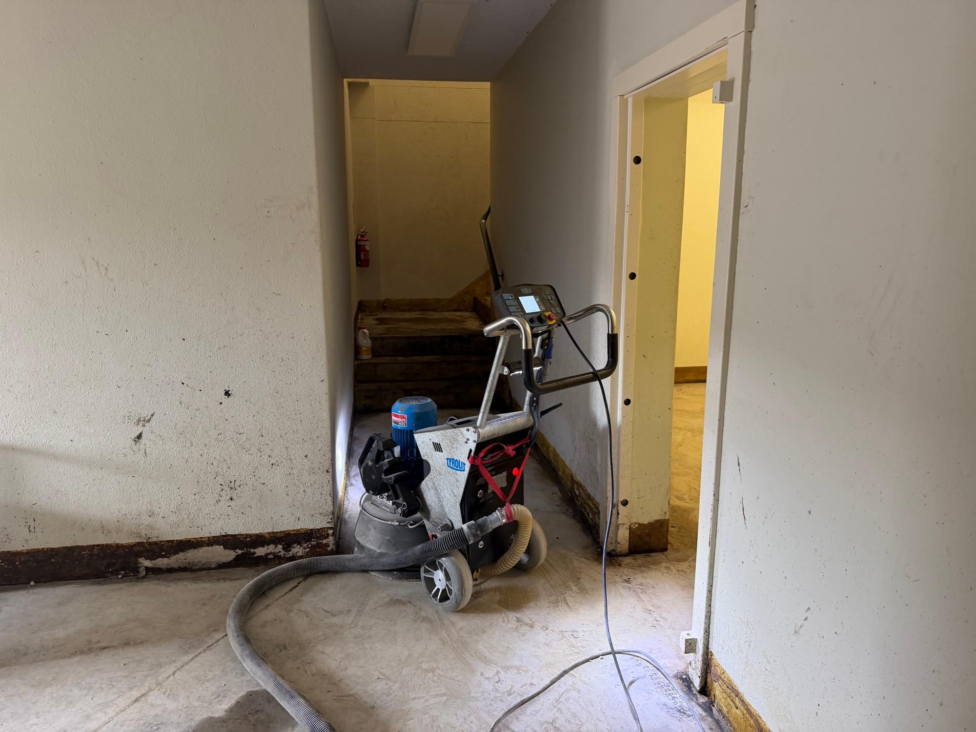 Edge grinding machine with vacuum extraction working a doorway beside the stairs