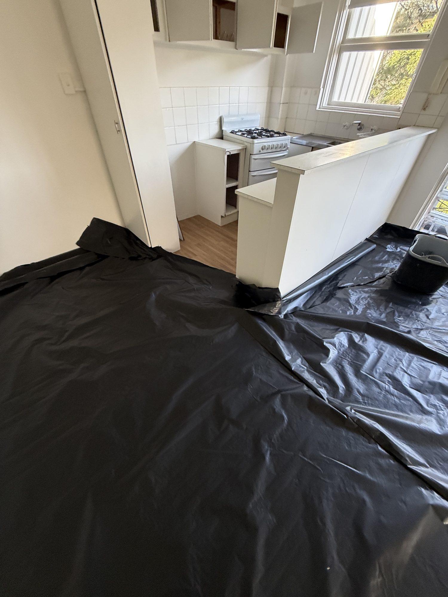 Plastic sheeting running up to the kitchen bench before the joinery was removed