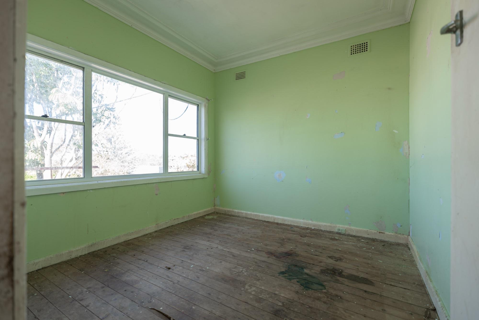 Bedroom stripped back to bare floorboards after water damage, ready for the builder