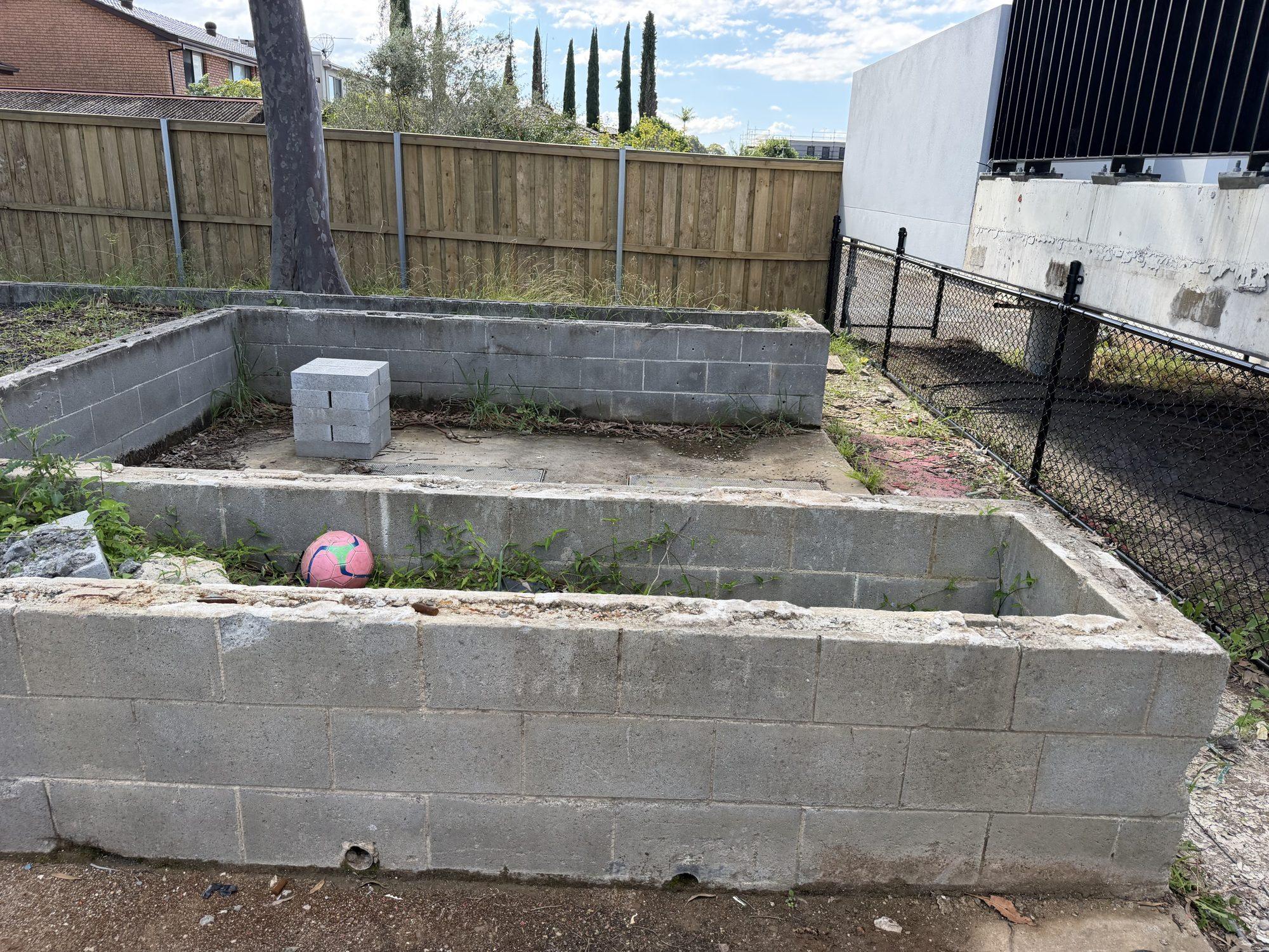 Waist-high besser block planter bed against the school boundary fence