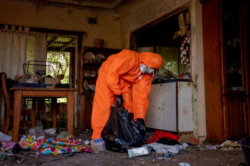Crew member in full PPE bagging contents in a squalor clean-out