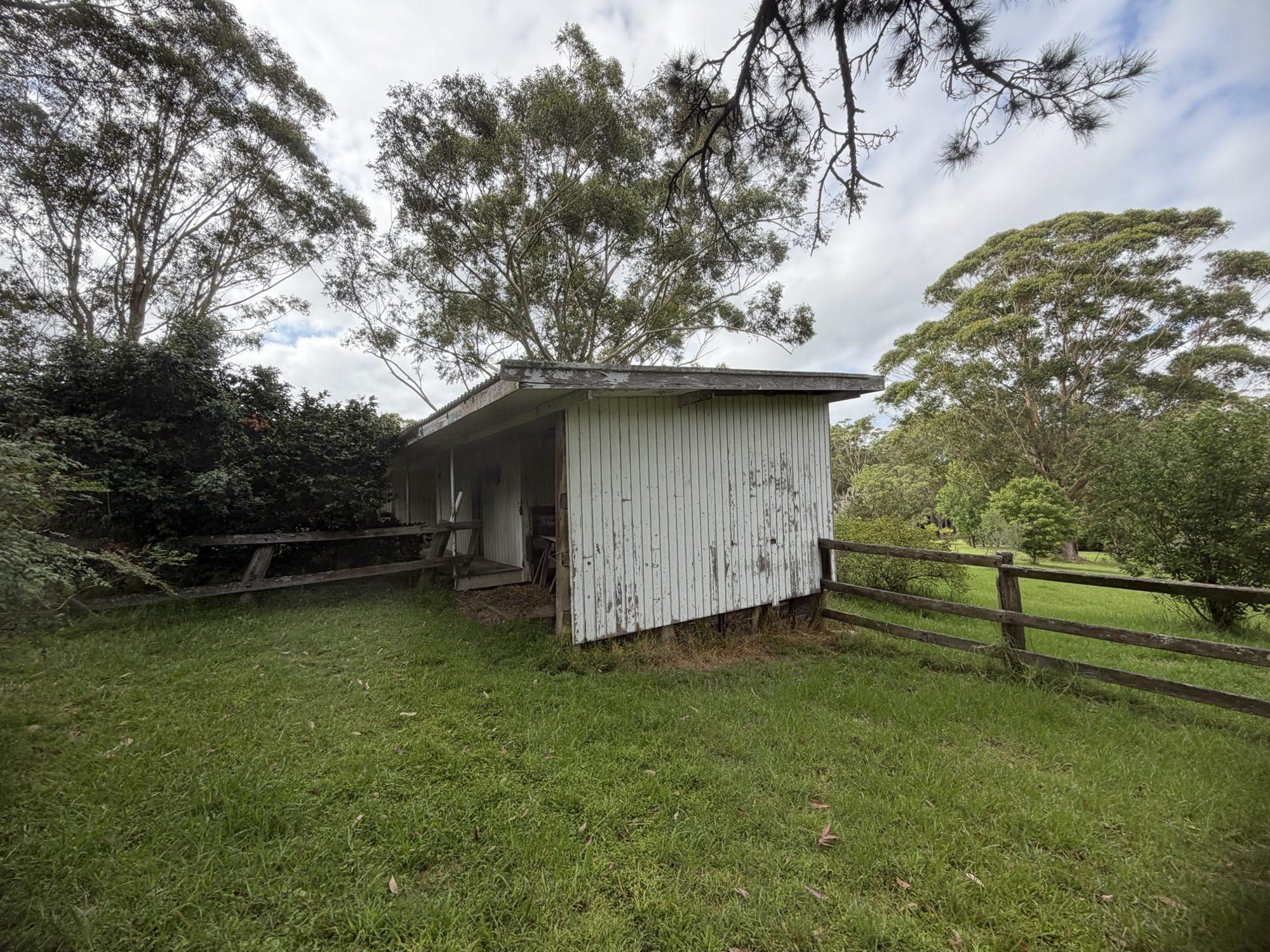 Side view of the long timber shed and post-and-rail fence before works