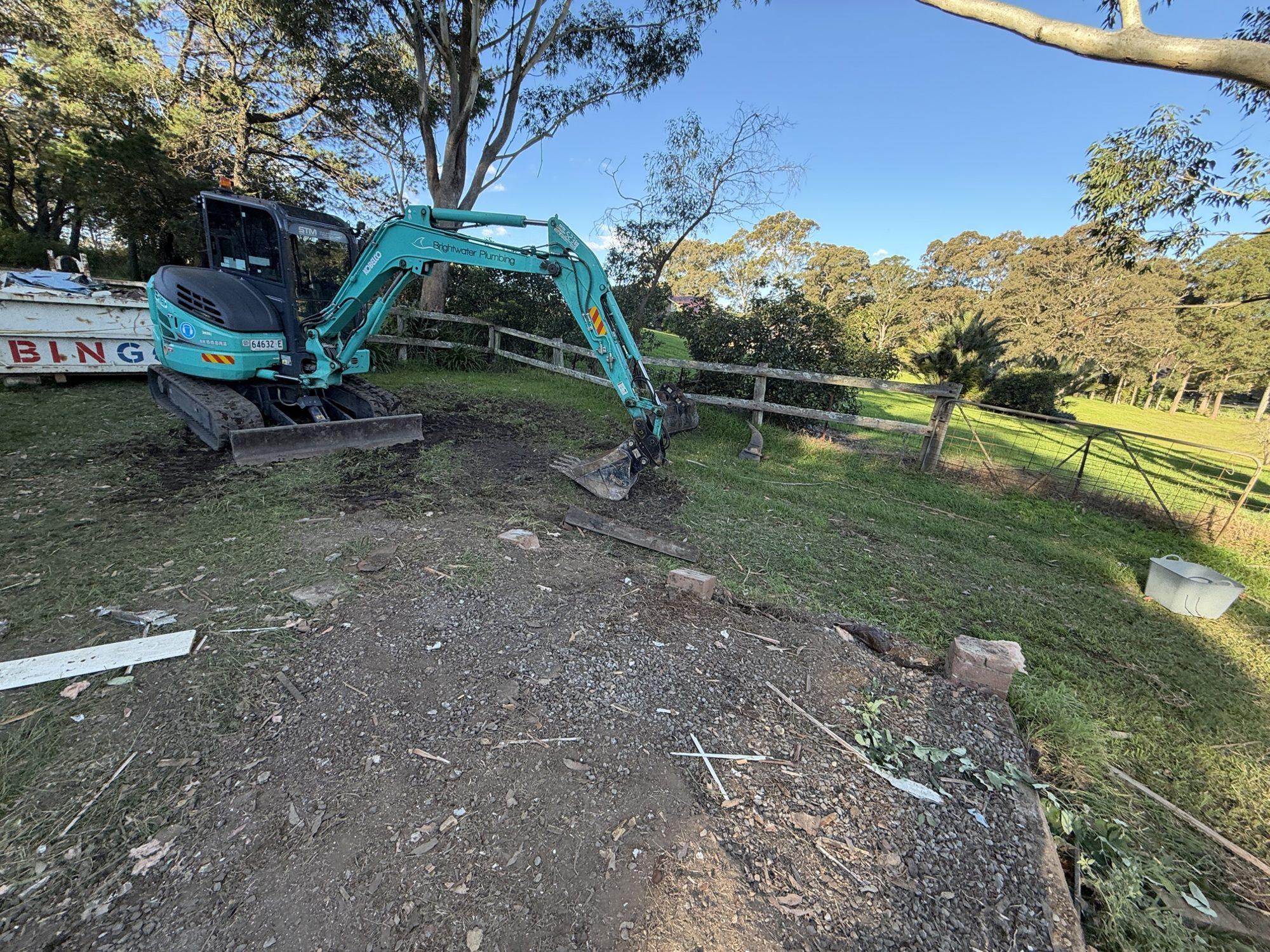 Excavator on the cleared shed site with the timber structure demolished