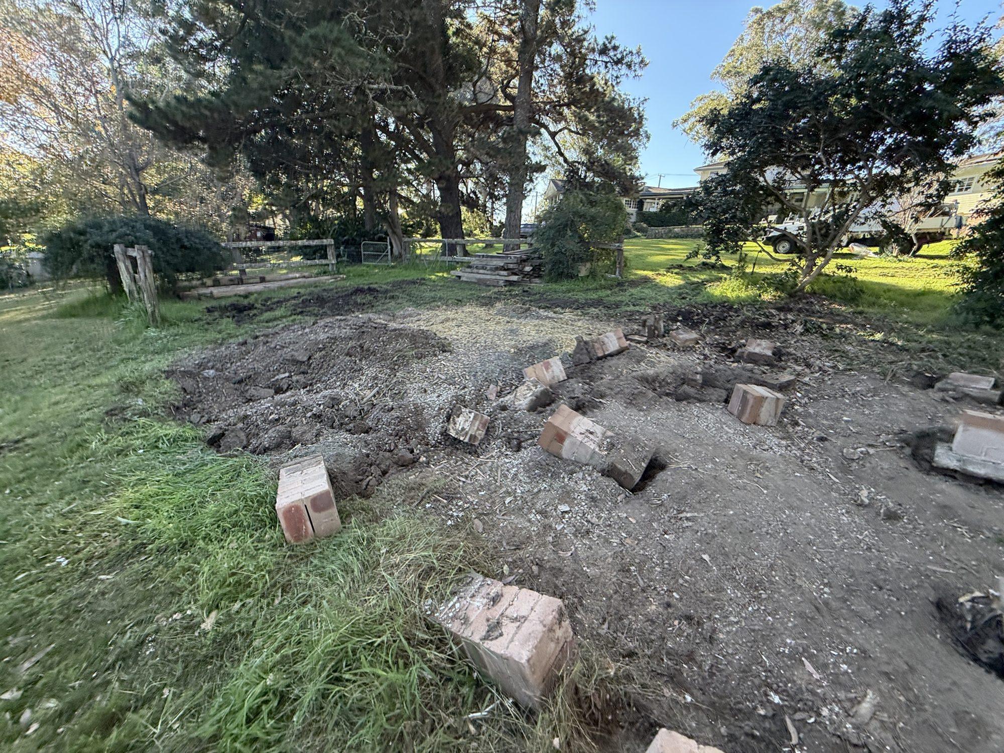 Cleared ground where the shed stood, with the brick piers being removed