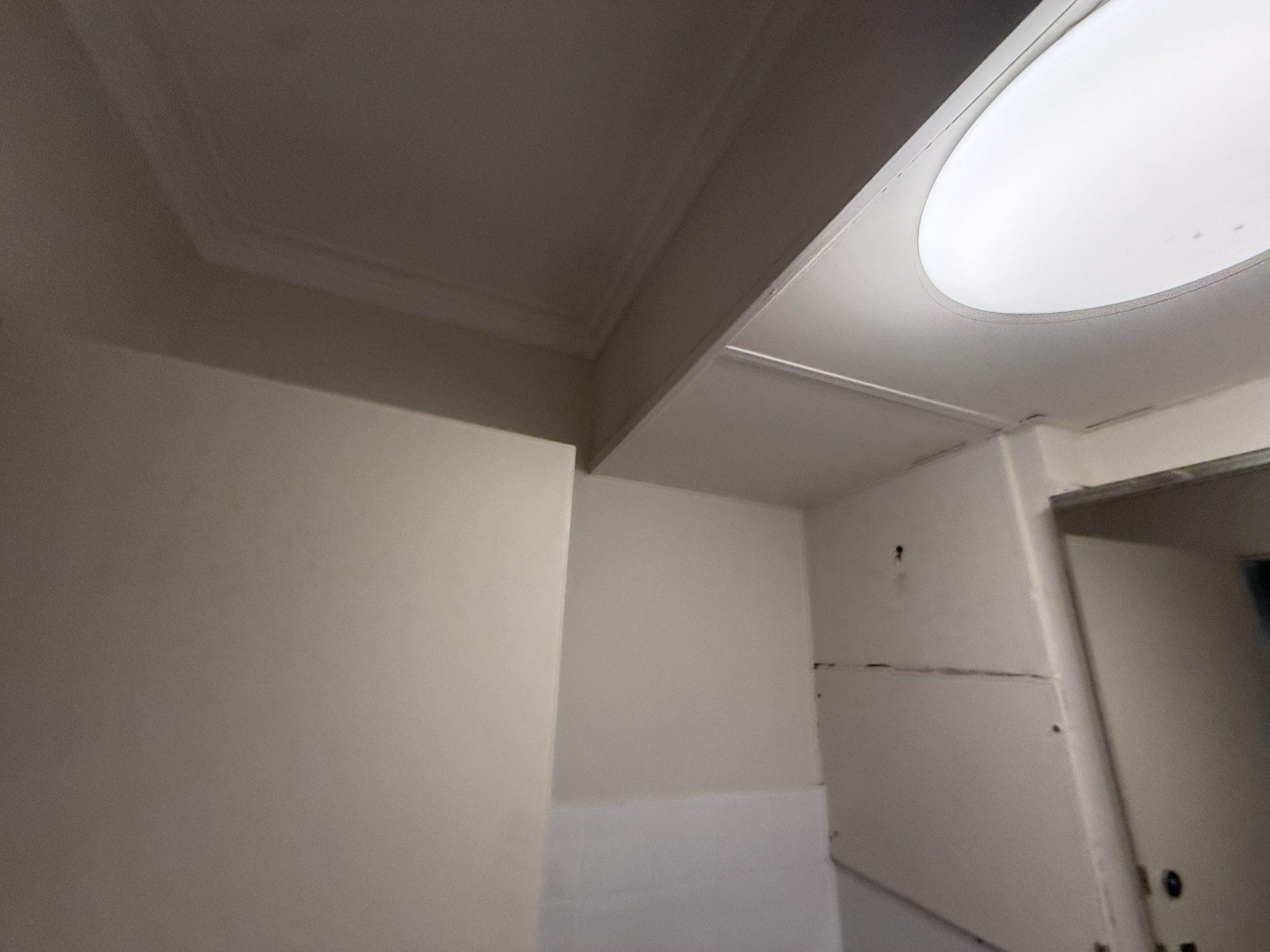 Original fibre-cement bathroom ceiling panel with a round light fitting before removal