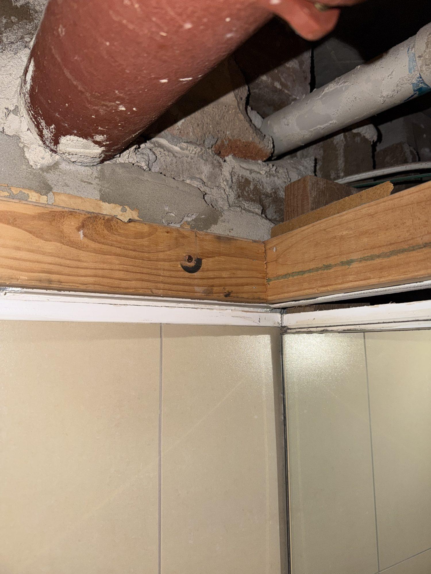 Pipes and the galvanised duct passing through the concrete slab above the timber ceiling frame