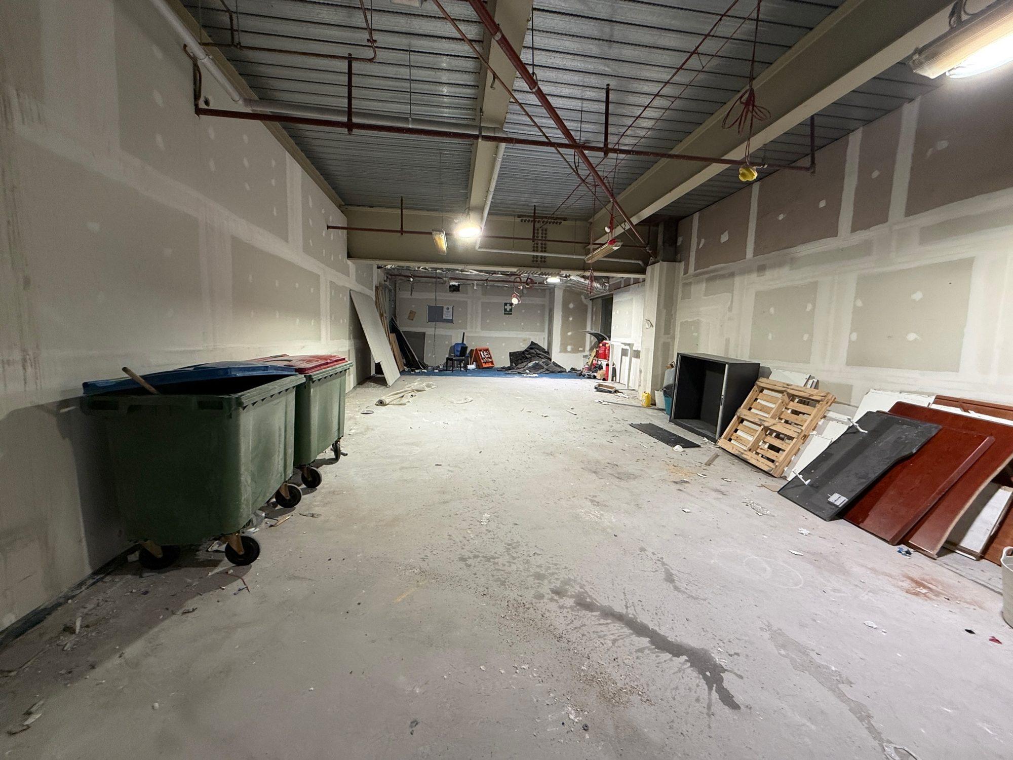 Loaded bins and dismantled joinery panels in a back-of-house area of Sydney Airport T1 during an overnight clear-out