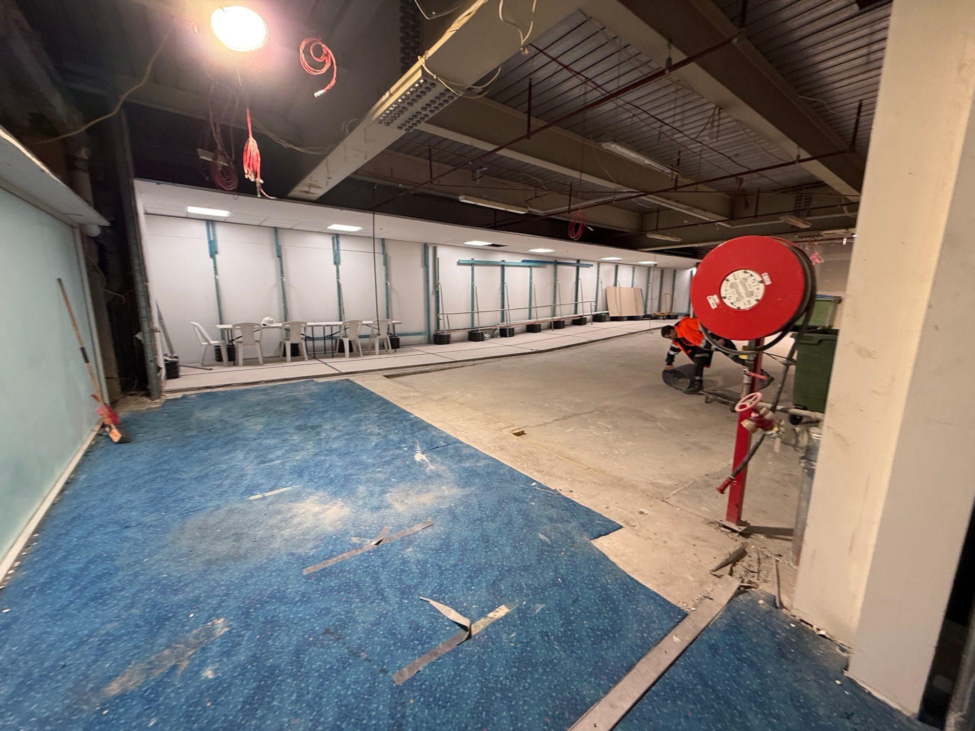 Floor finishes being removed from the slab in a back-of-house area of Sydney Airport T1