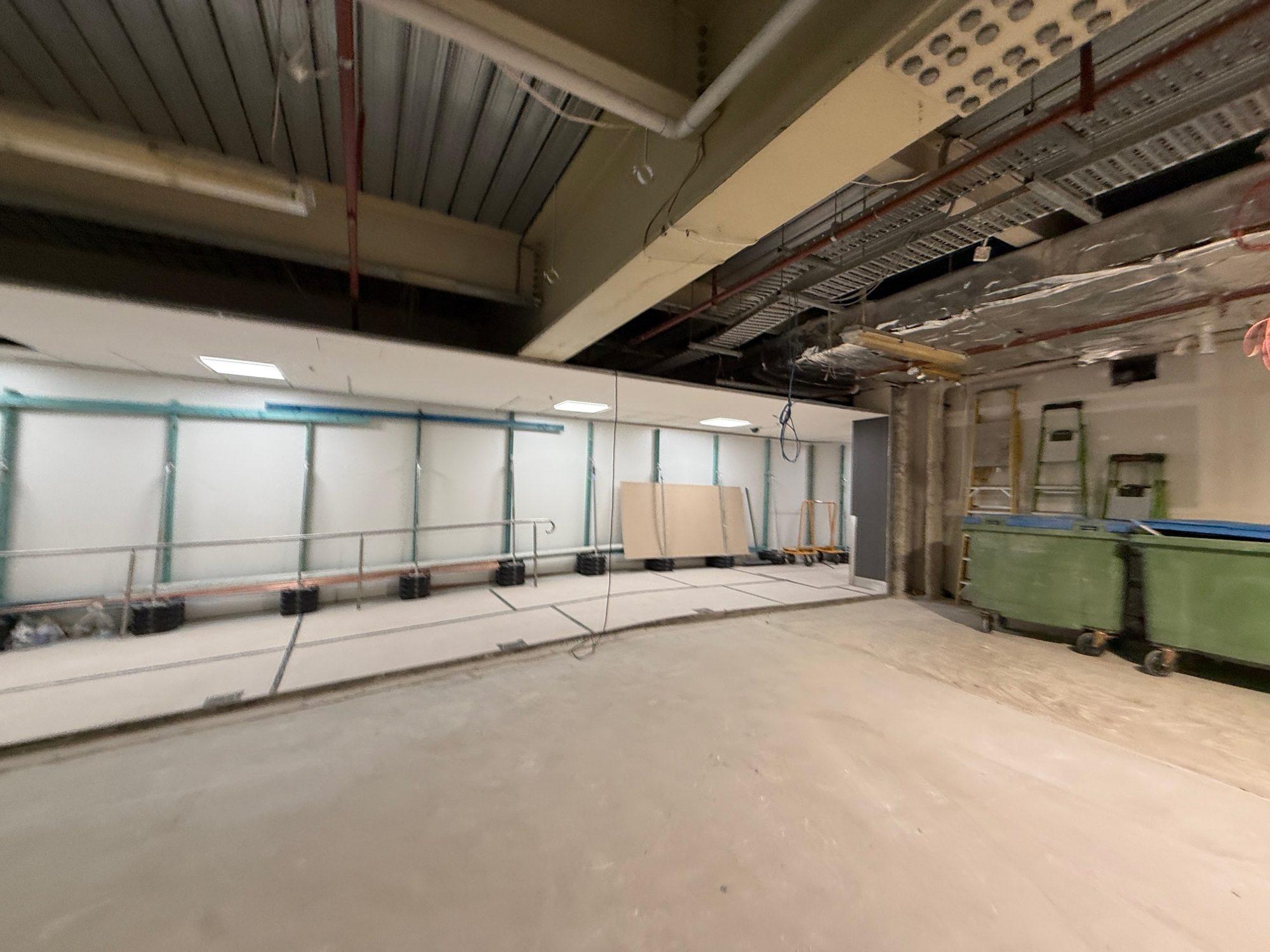 Loaded bins staged against the wall of a cleared back-of-house room inside Sydney Airport T1