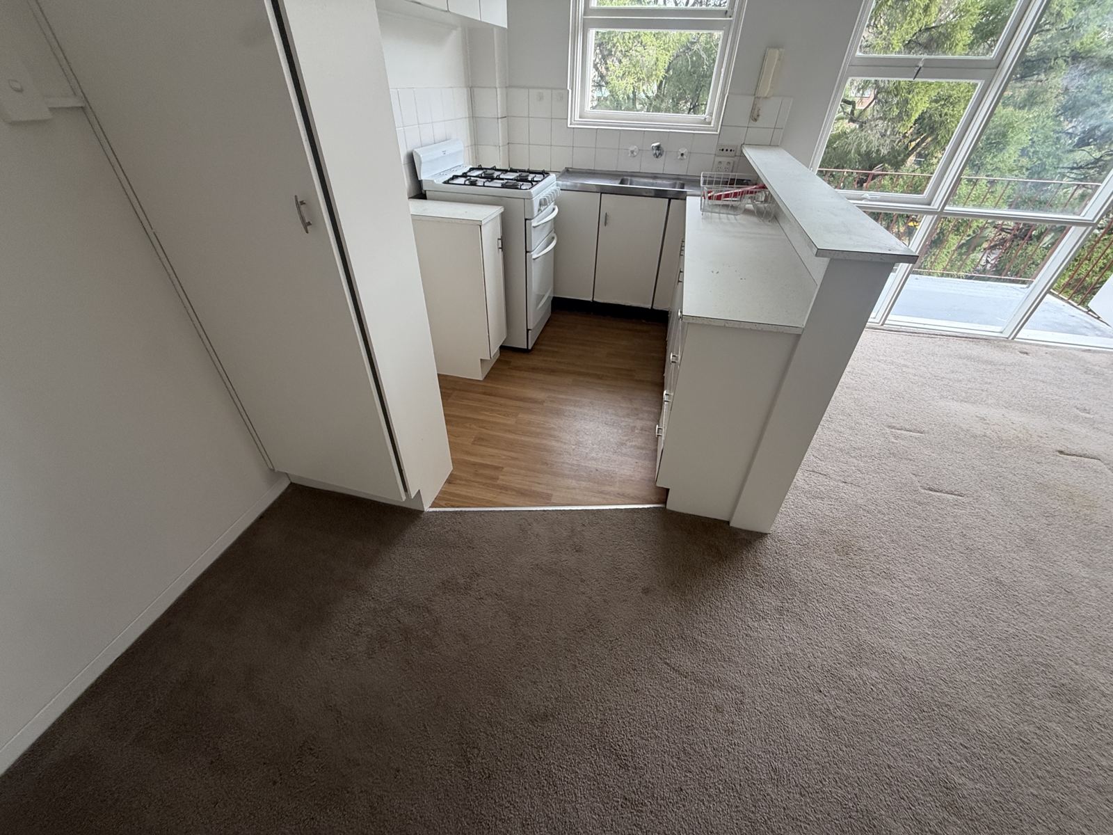 Vacant apartment kitchen in Crows Nest with the original vinyl floor, photographed before the asbestos removal and strip-out